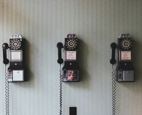 Drei alte Telefone an einer Wand – Symbol für klassische Kommunikation